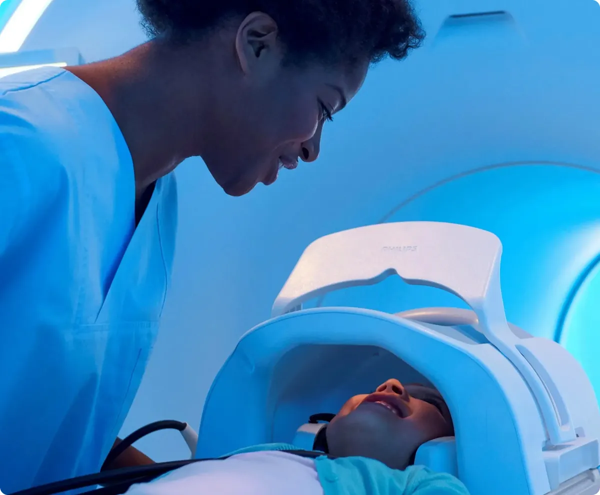 Female nurse smiling at girl who is laid down as she enters an MRI scanner