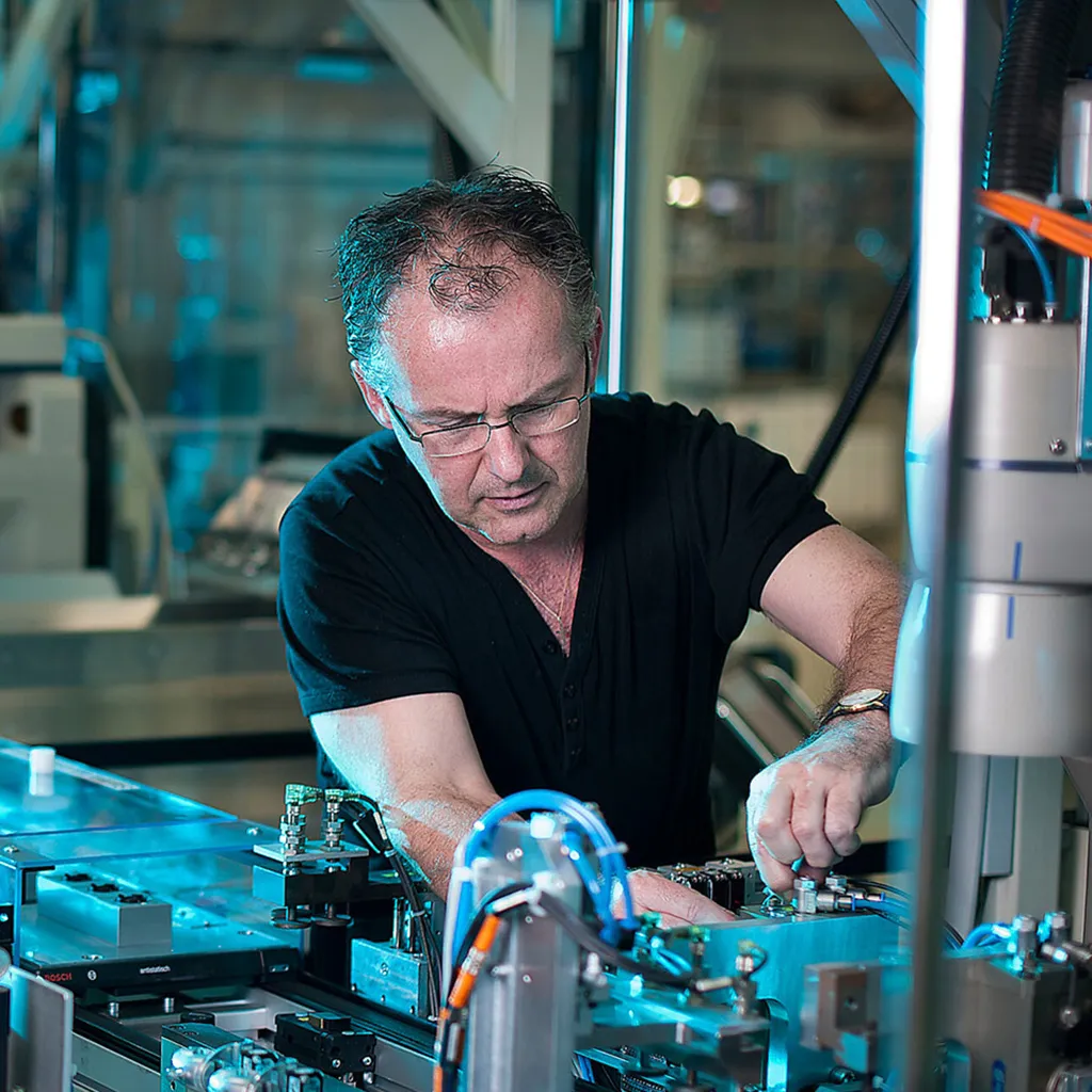 An older male engineer wearing glasses operating a machine.