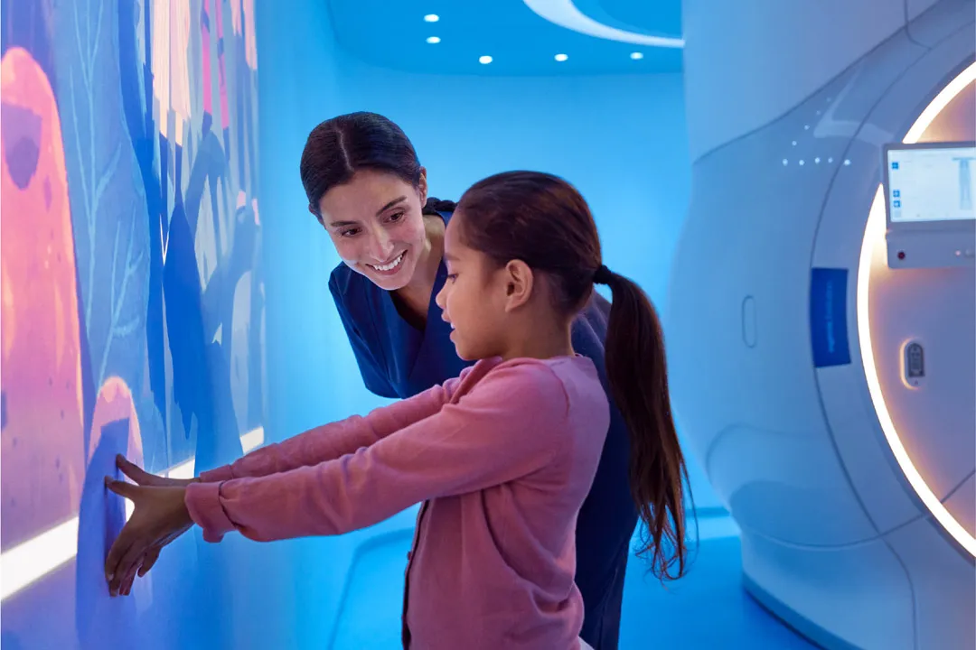 Female nurse smiling at girl next to a wall with a projected image